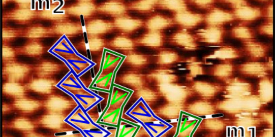 Ein durch ein Rastertunnelmikroskop aufgenommenes Bild des Moleküls Theobromin, das sich in einer Zick-Zack-Anordnung auf einer Gold-Oberfläche anordnet.